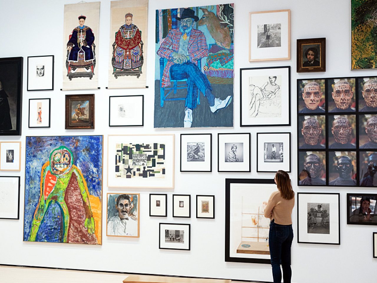 Photo of a woman looking at a wall of artwork