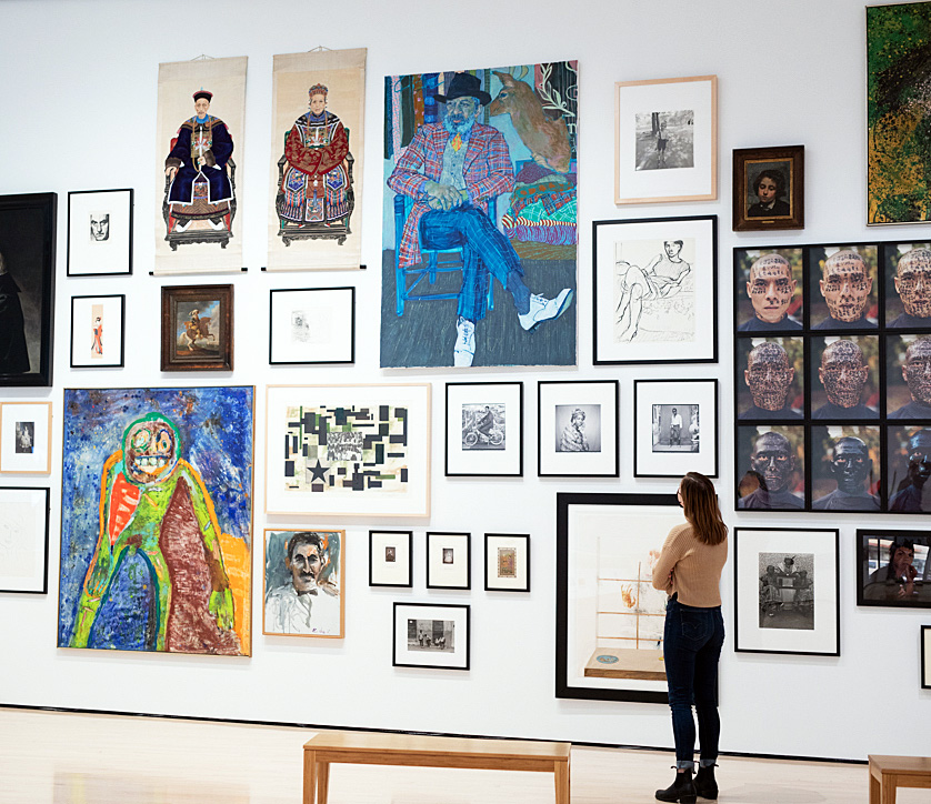 Photo of a woman looking at a wall of artwork