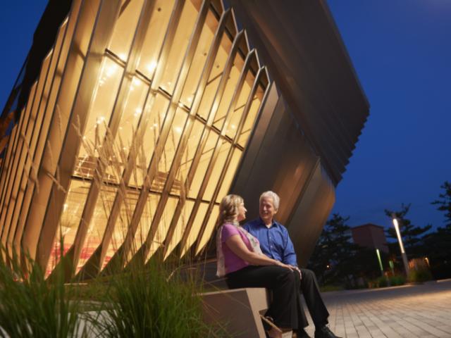 photo of a couple sitting in front of the Broad Art Museum in the evening