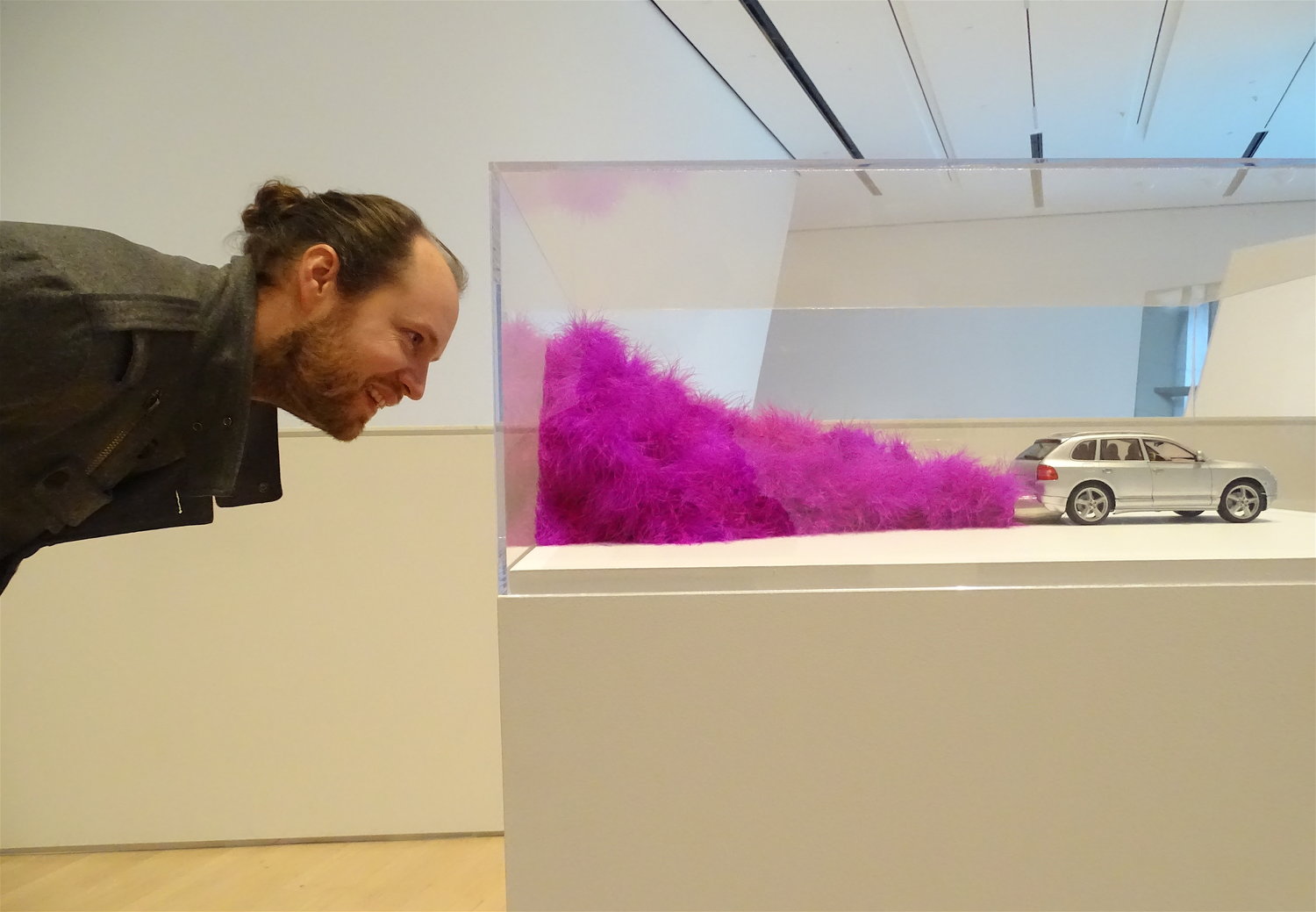 Photo of Steve Bridges looking at an art piece that depicts a model of a car with purple exhaust