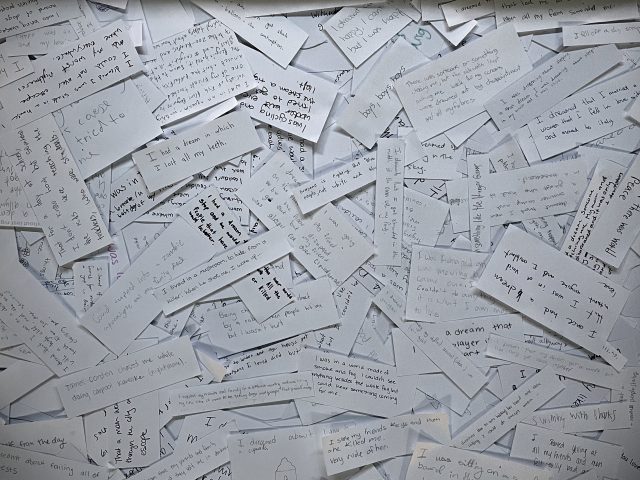 A pile of white paper cards with handwritten messages on them.