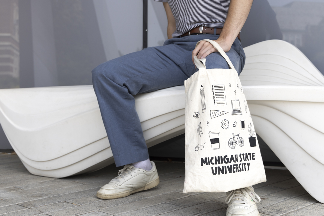 Screenprinted tote bag being held next to a person sitting down