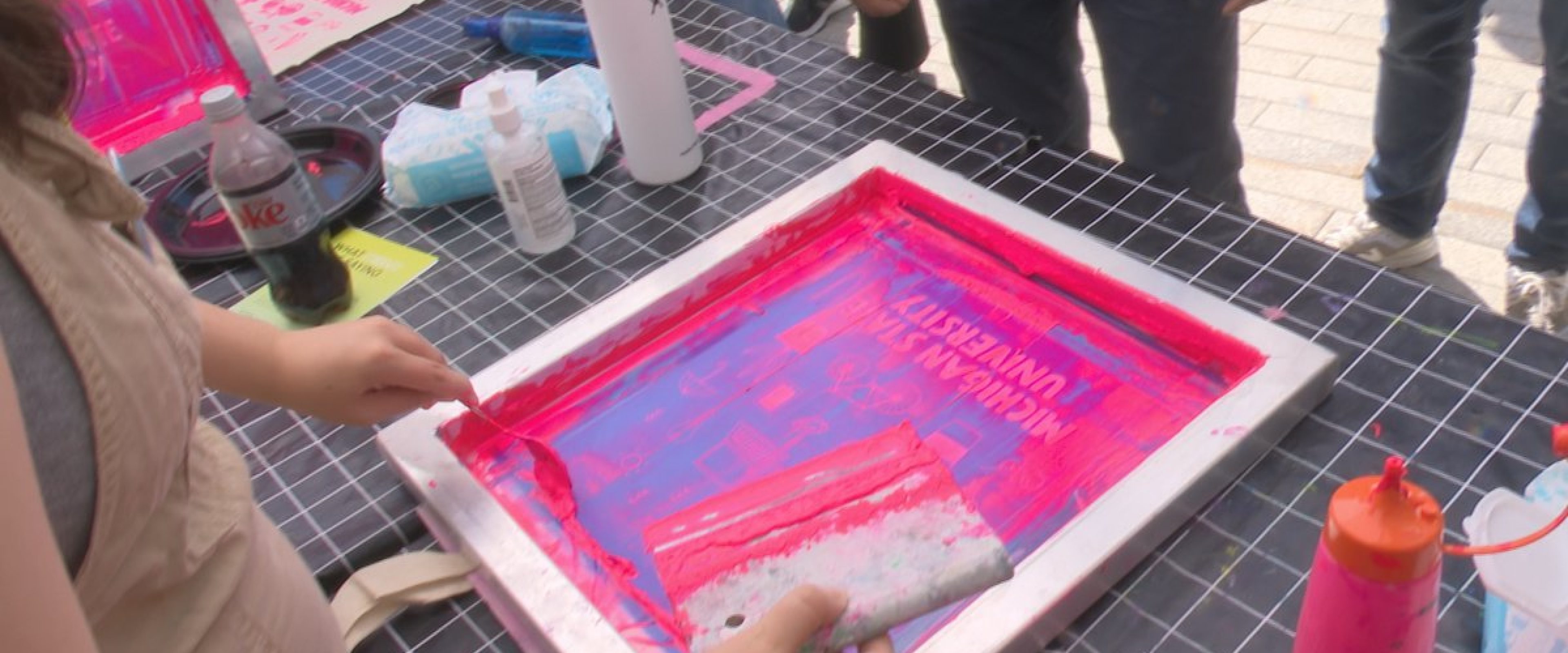 Someone using a screen print with pink ink