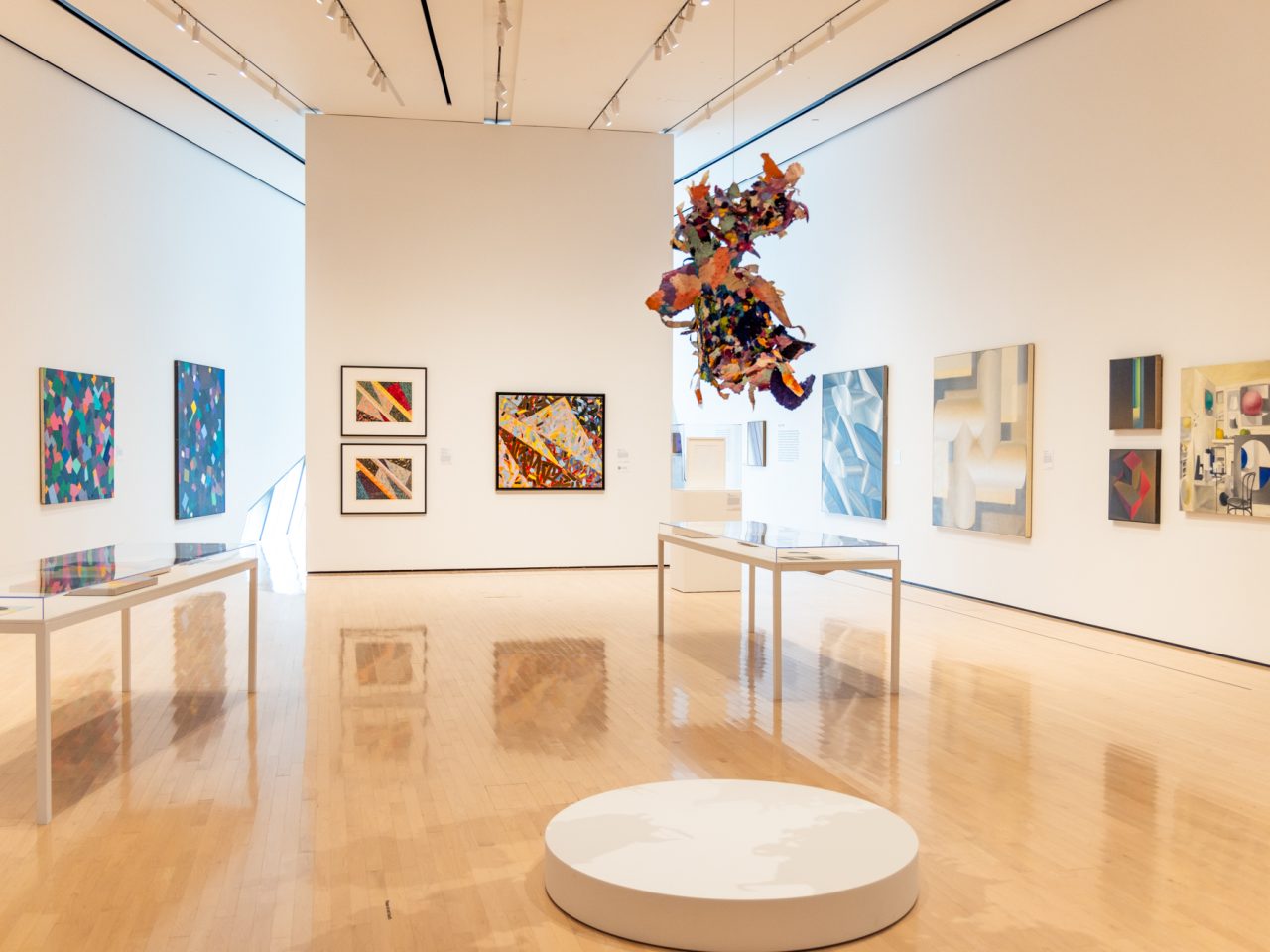 Gallery of abstract paintings on walls and paper structure hanging from above