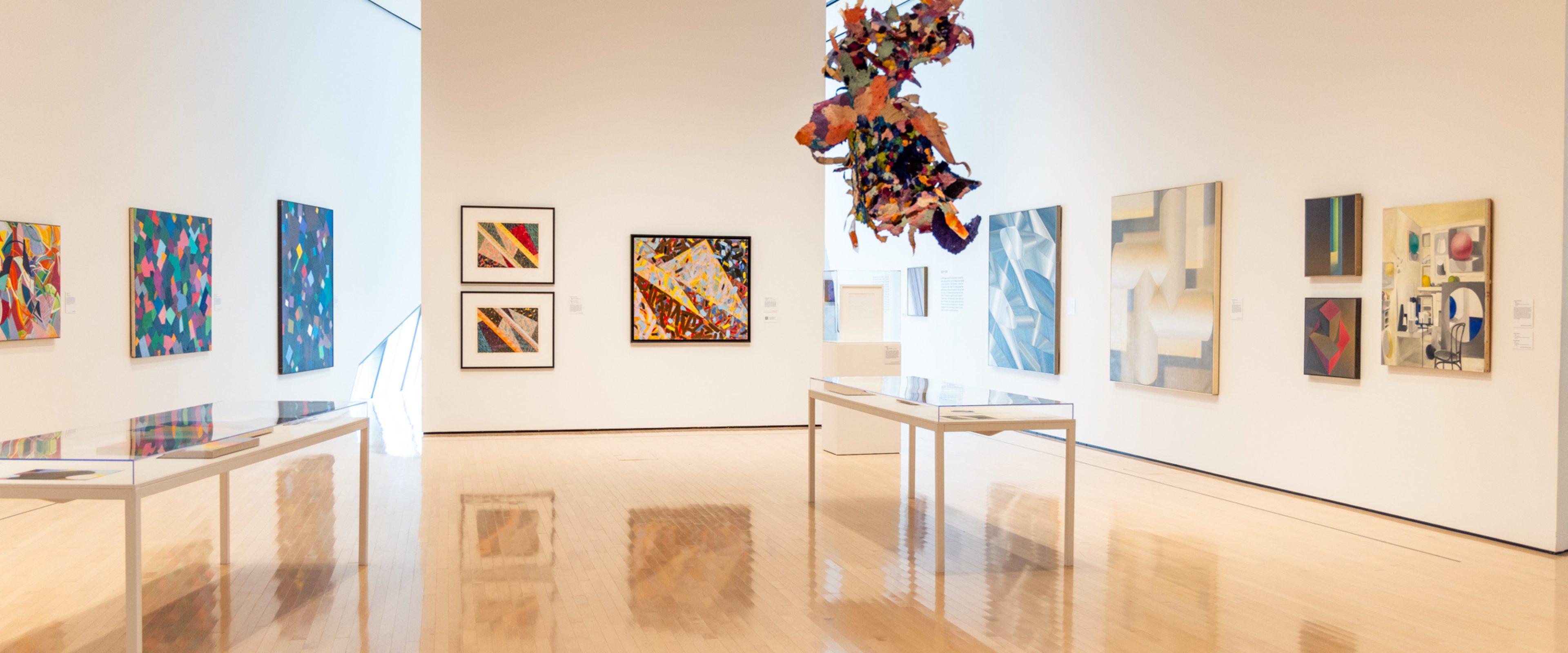 Gallery of abstract paintings on walls and paper structure hanging from above