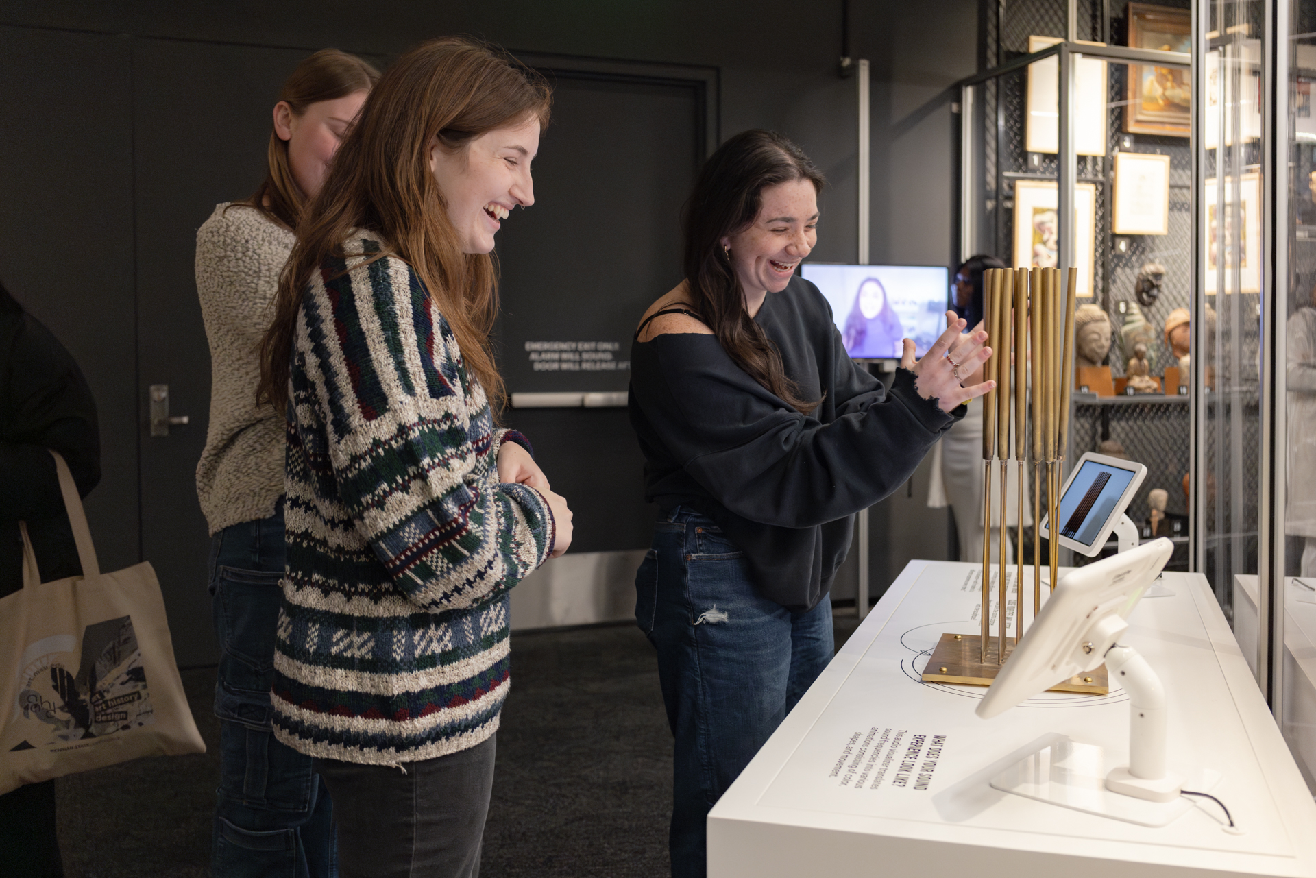 A group of three students interacting with a sculpture