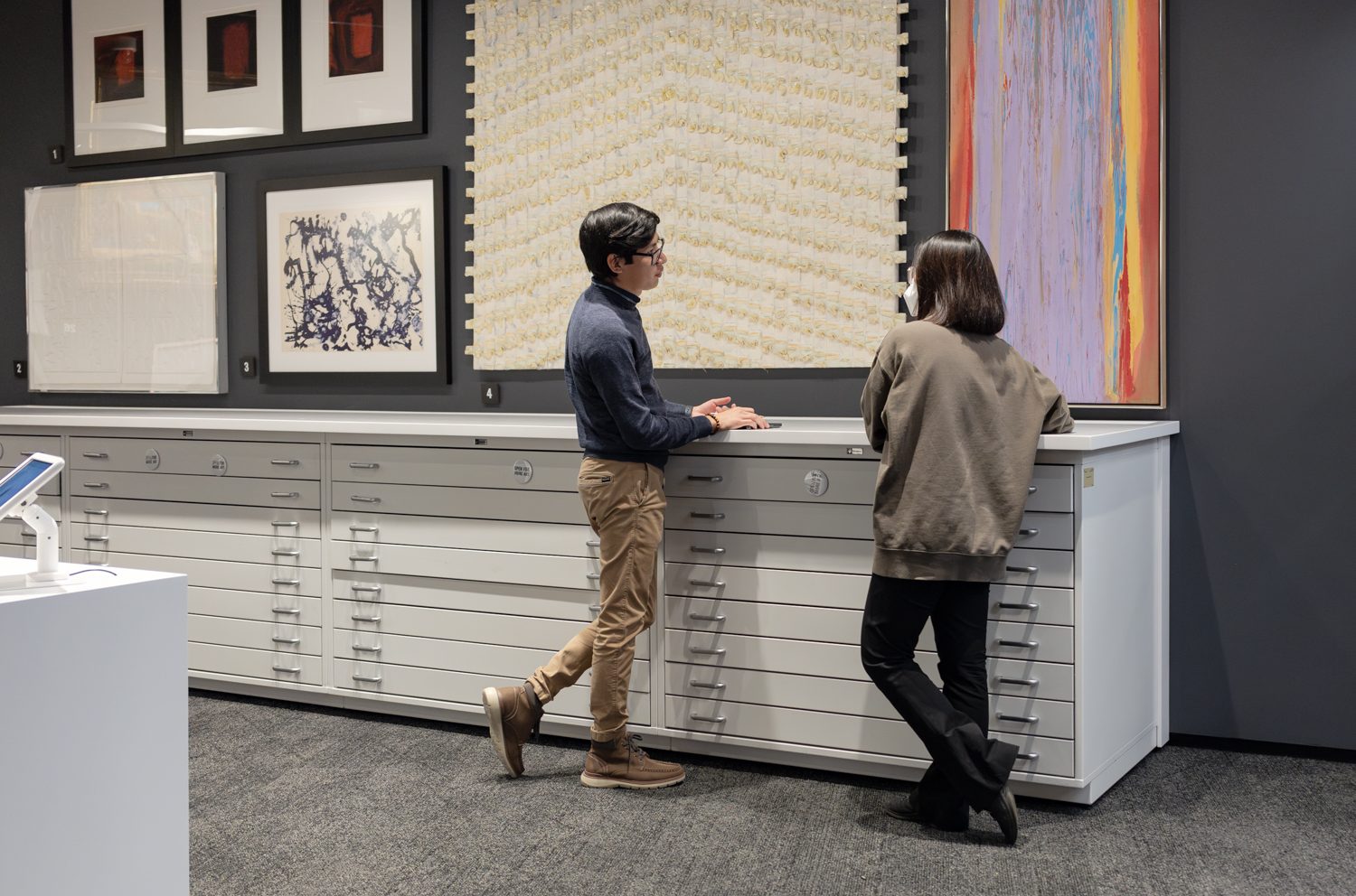Two people standing at a counter looking at art