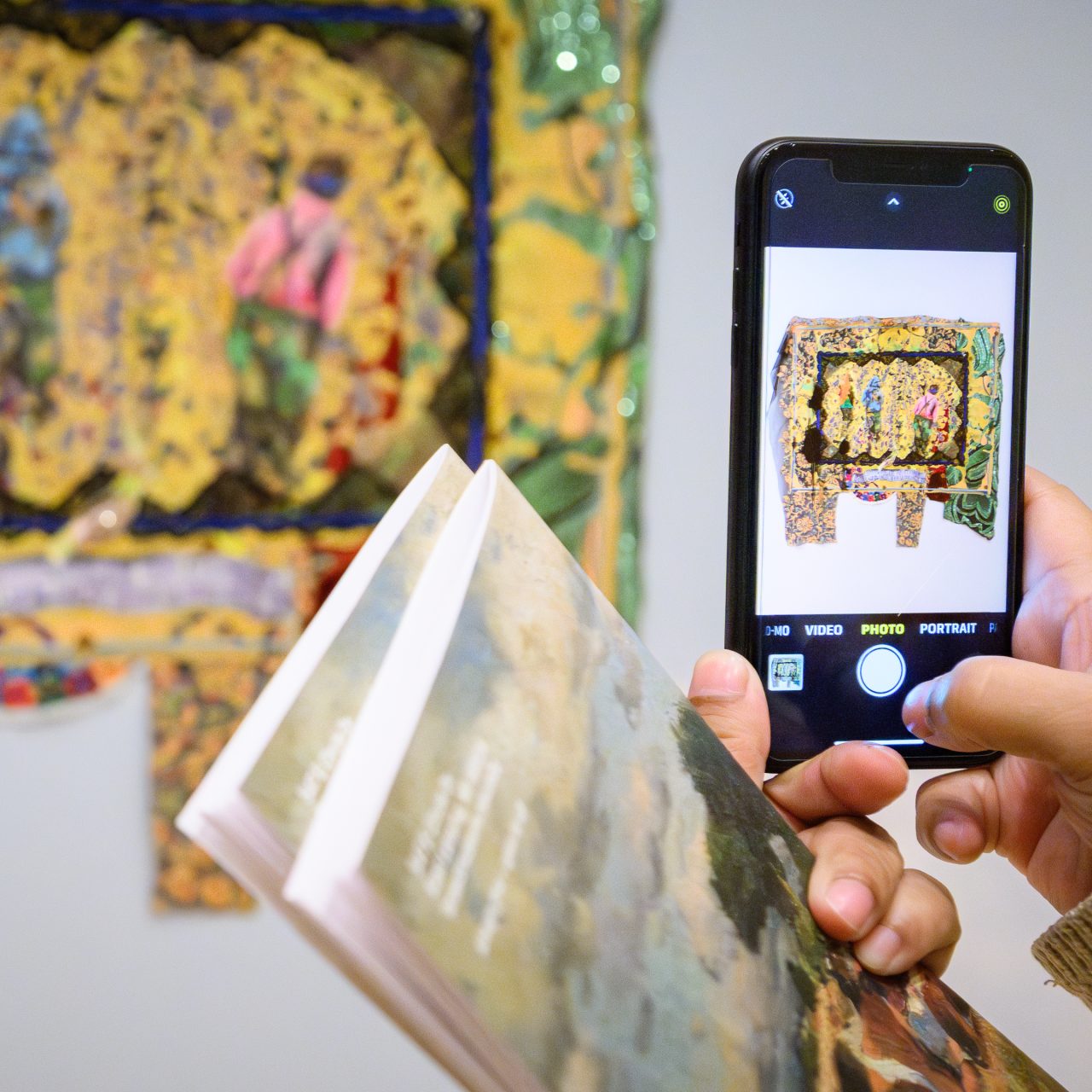 A picture of someone taking a picture of art hanging on the wall