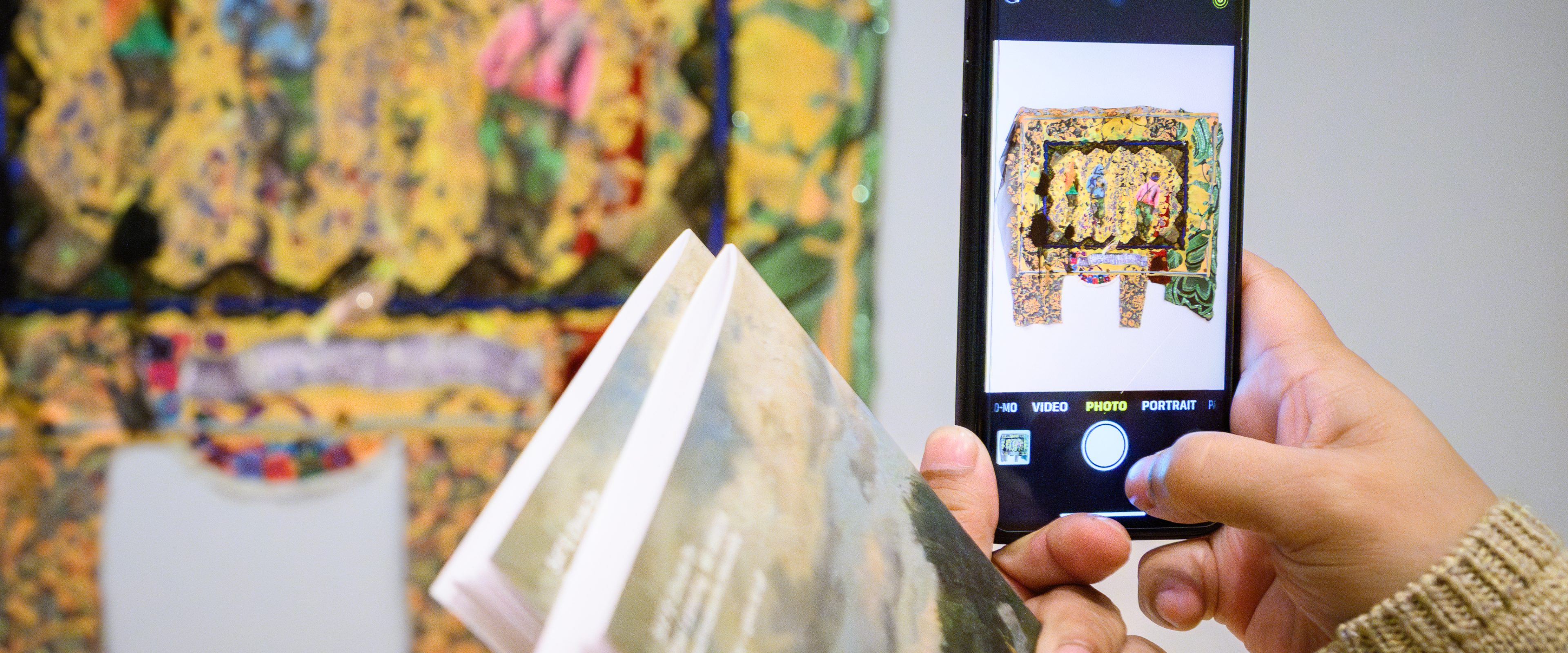 A picture of someone taking a picture of art hanging on the wall